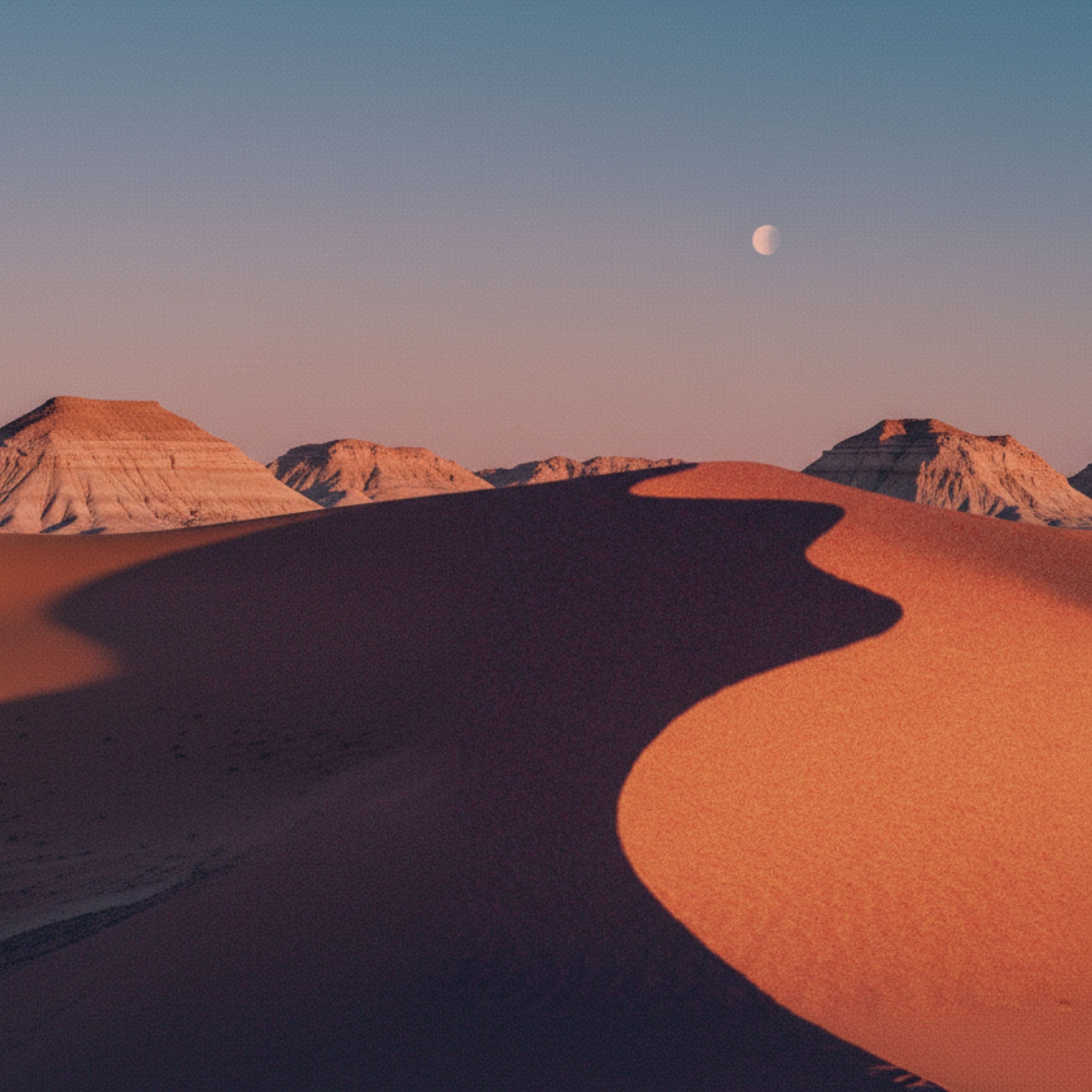 Desert sand dunes at dusk beneath the moon